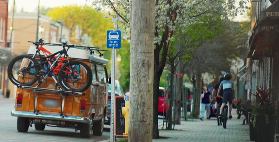Creemore Street, a bus stop sign, a car with a bike and a guy riding a bike