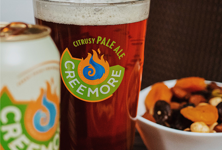A glass of glass with Citrus Pale Ale beer next to a can of Pale Ale and a bowl with seeds
