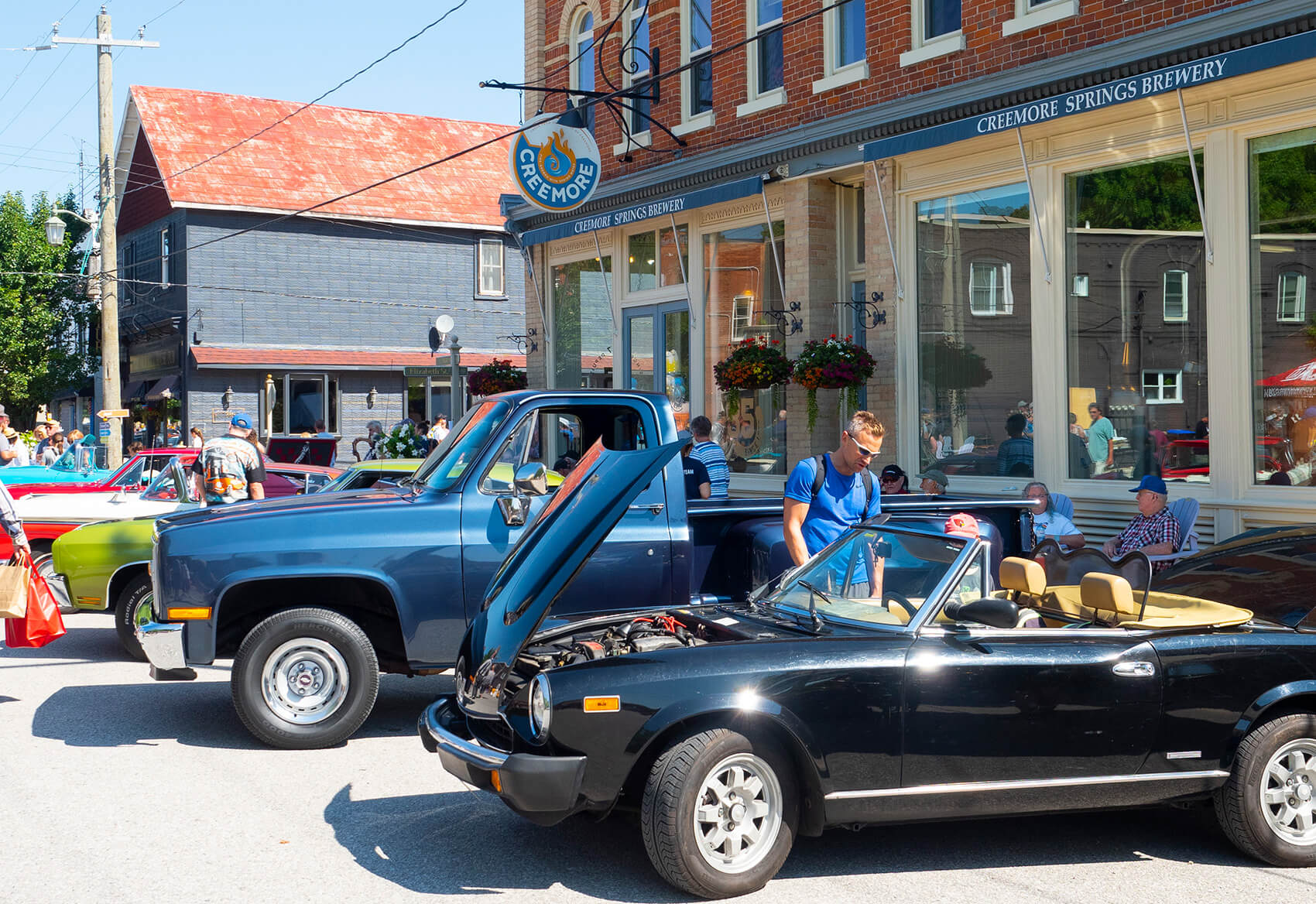 Black Classic Car showing engine, person looking inside the car