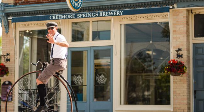 person in a vintage bicycle say hello with a hand